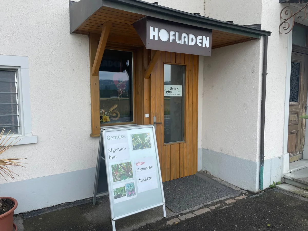 Bild von einem Hauseingang, über der Tür hat es ein Schild mit der Aufschrift «Hofladen».